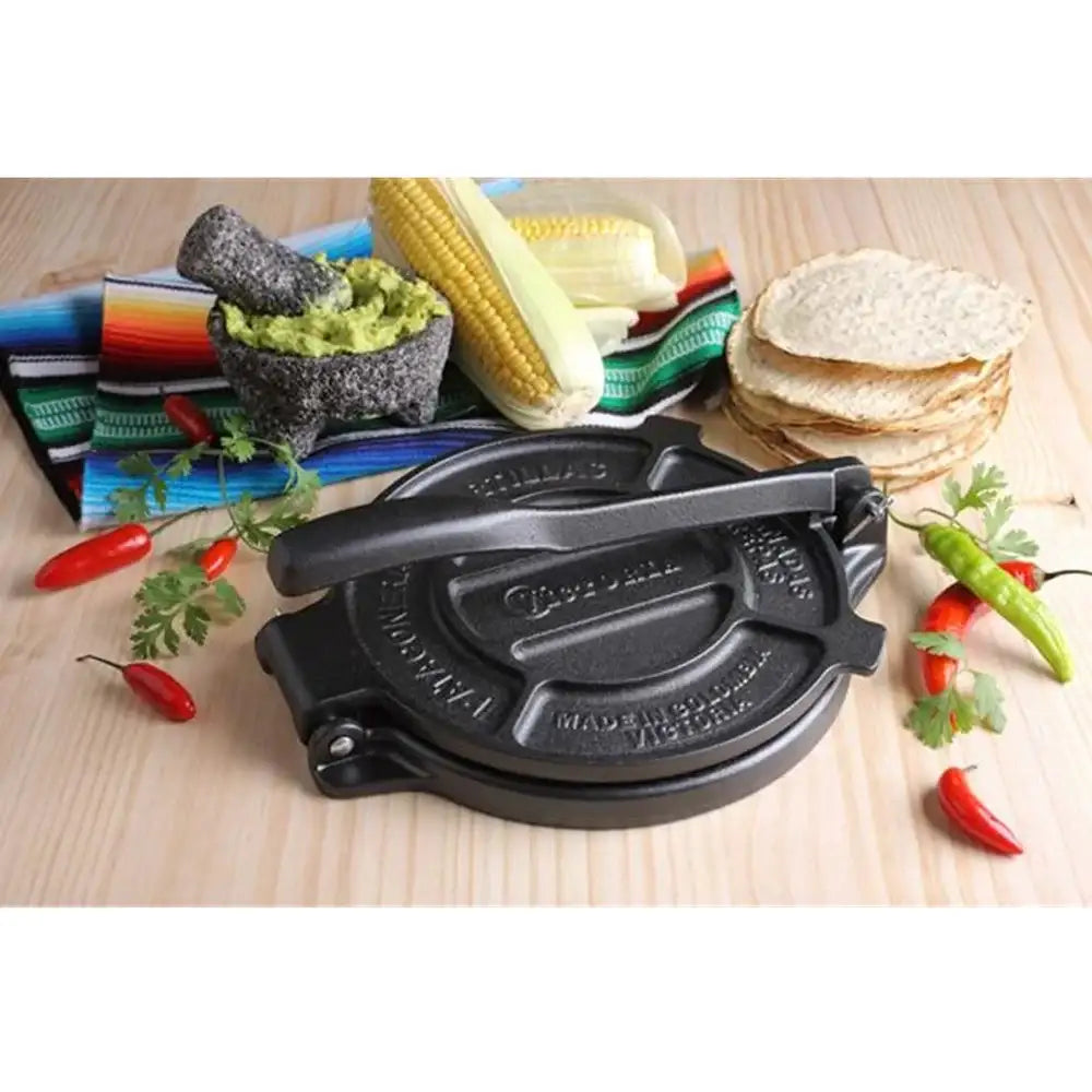 Black tortilla press with ingredients on a wooden surface