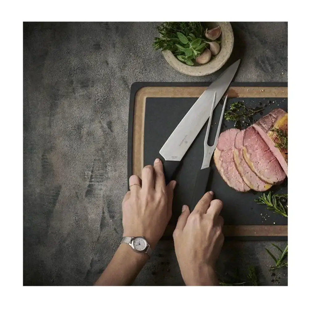 Person preparing food with a knife on a cutting board, surrounded by sliced meat and herbs.