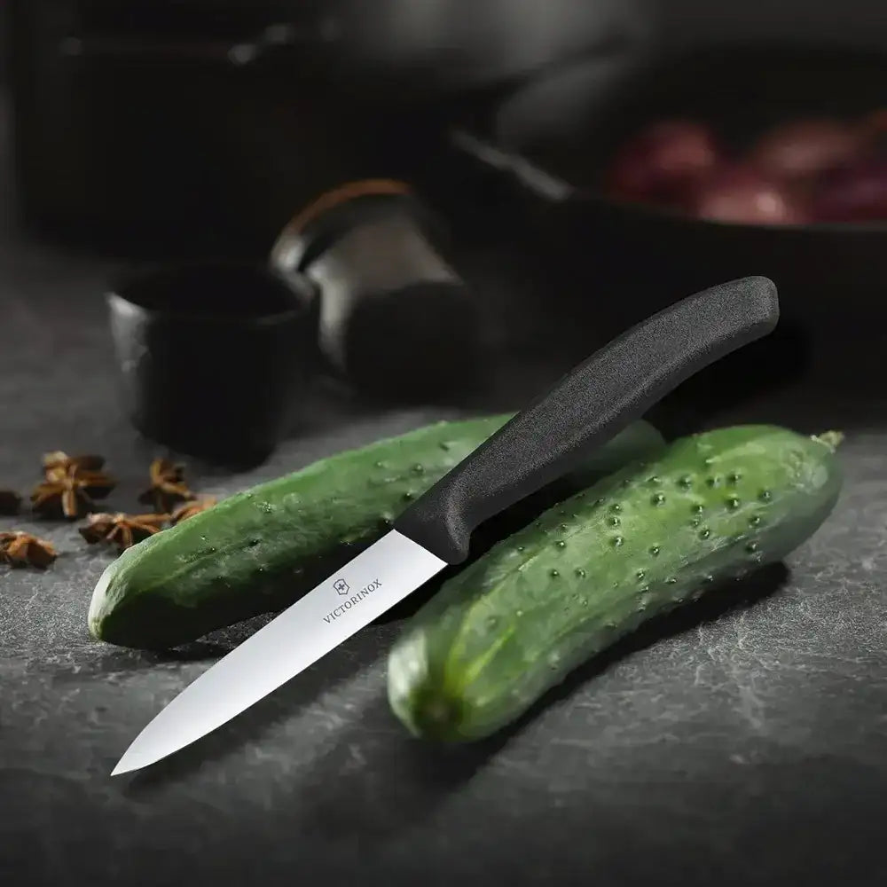 Paring knife on a cucumber with a dark background