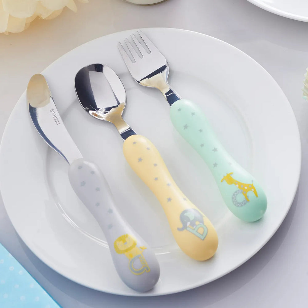 Set of children's cutlery including spoon, fork, and knife on a white plate with cartoon animal designs.
