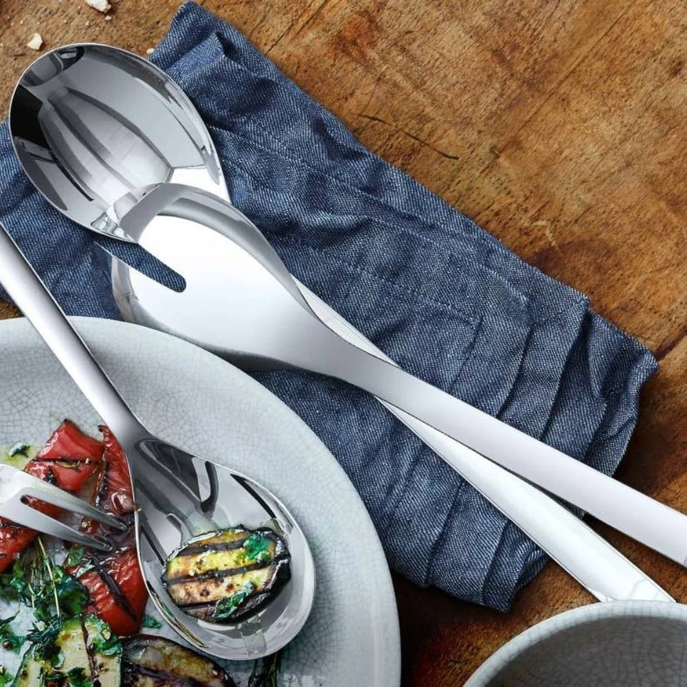 Stainless steel salad servers on a wooden surface with a blue napkin.