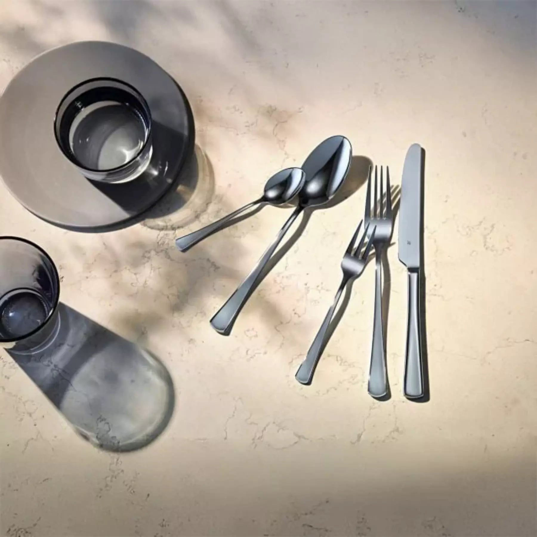 Silver cutlery set with glasses on a textured surface