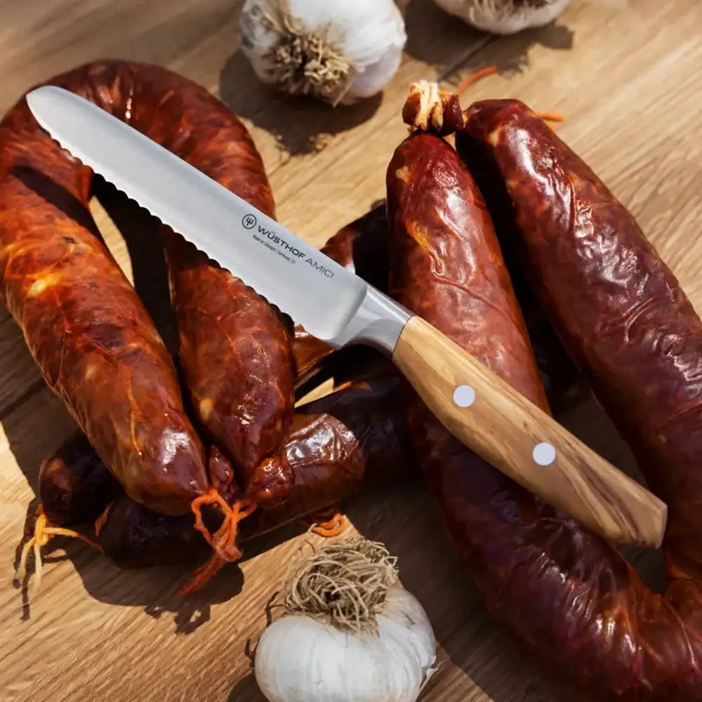 Knife with a wooden handle on sausages and garlic on a wooden surface