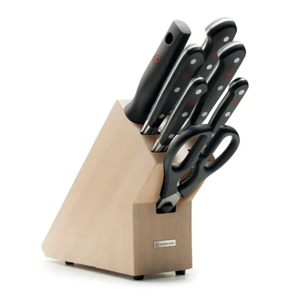 Set of knives with black handles in a beige knife block on a white background