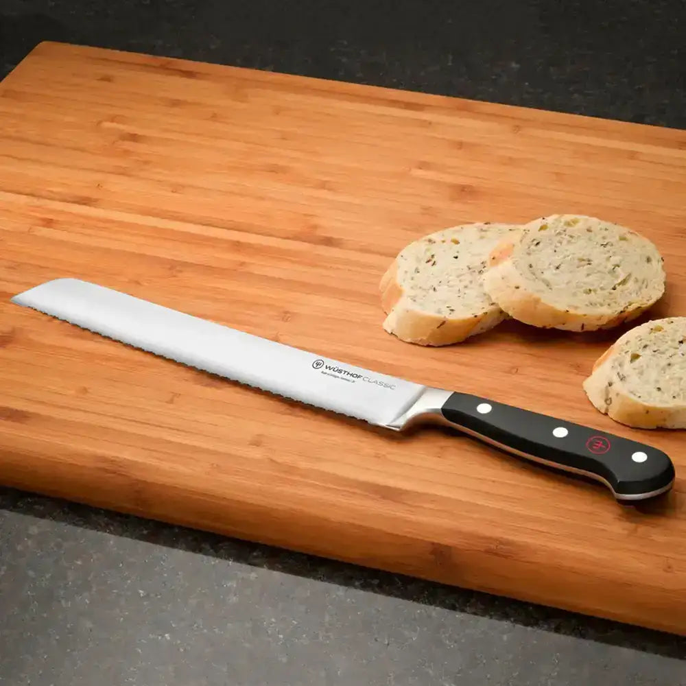 Bread knife on a wooden cutting board with sliced bread