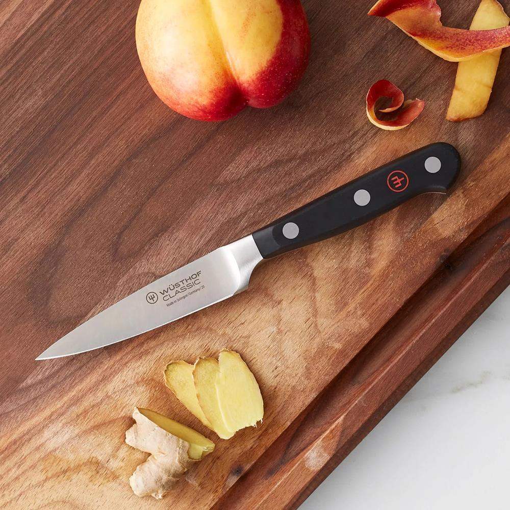 Wusthof knife on a wooden cutting board with apples and ginger