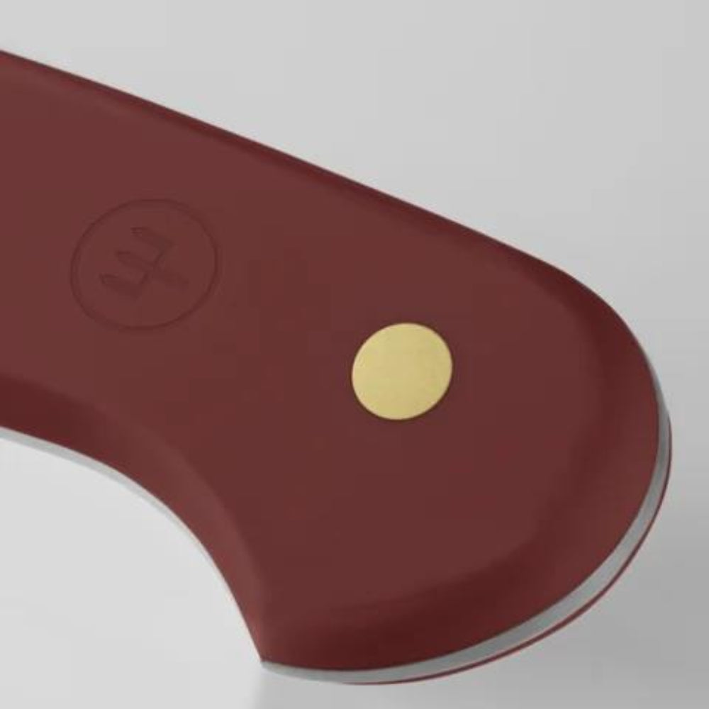Close-up of a knife handle with a gold dot on a gray background