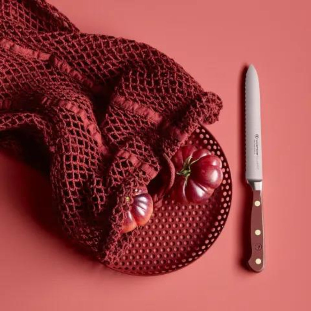 Red mesh bag with tomatoes and a knife on a red background