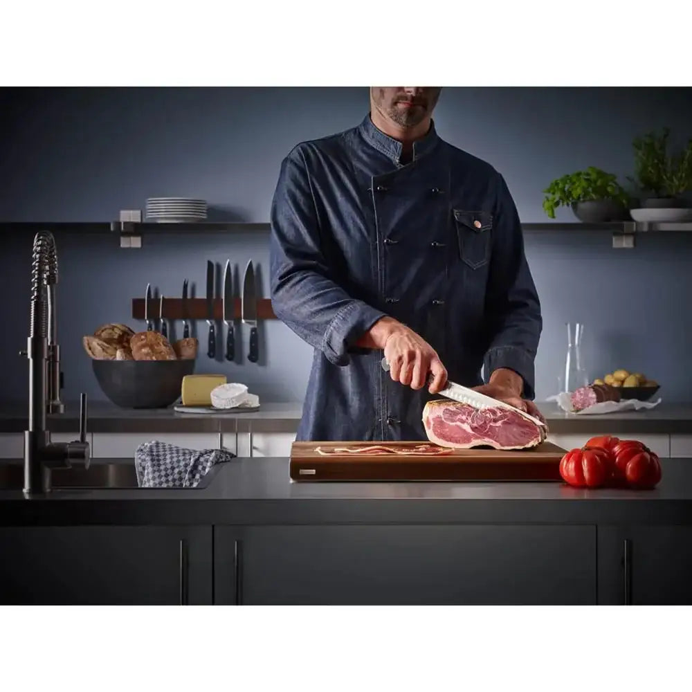 Chef cutting meat on a wooden board in a kitchen setting