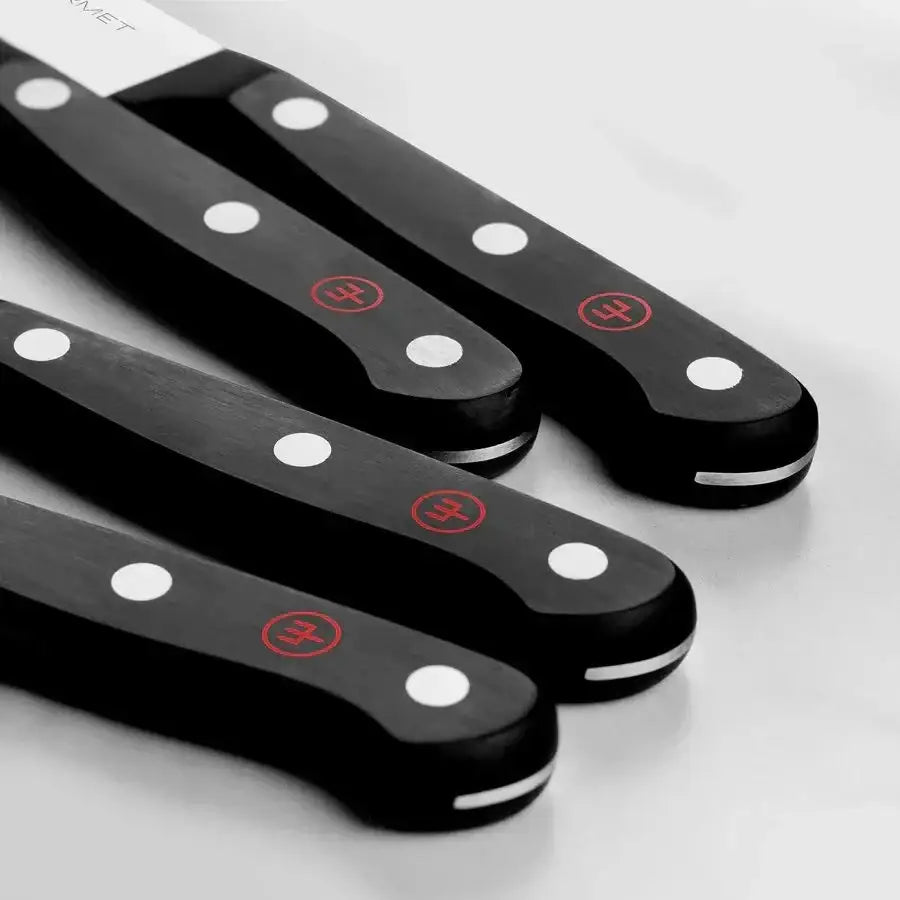 Set of black knives with white dots and red logos on a light gray background