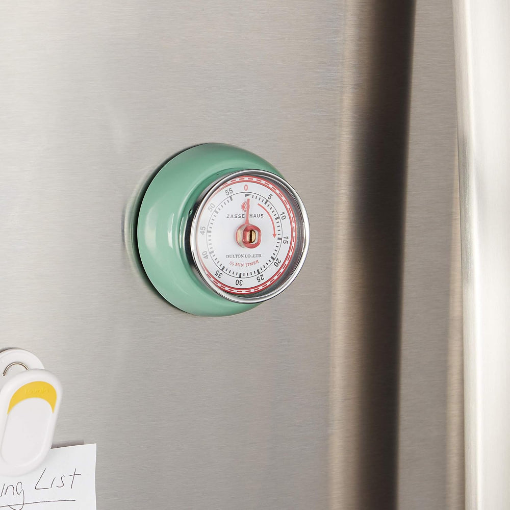 Mint green temperature gauge on a refrigerator door with a pink face.