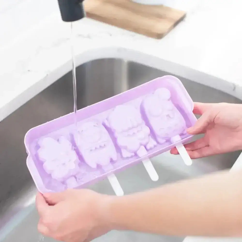 Purple silicone popsicle mold being rinsed under running water in a kitchen sink.