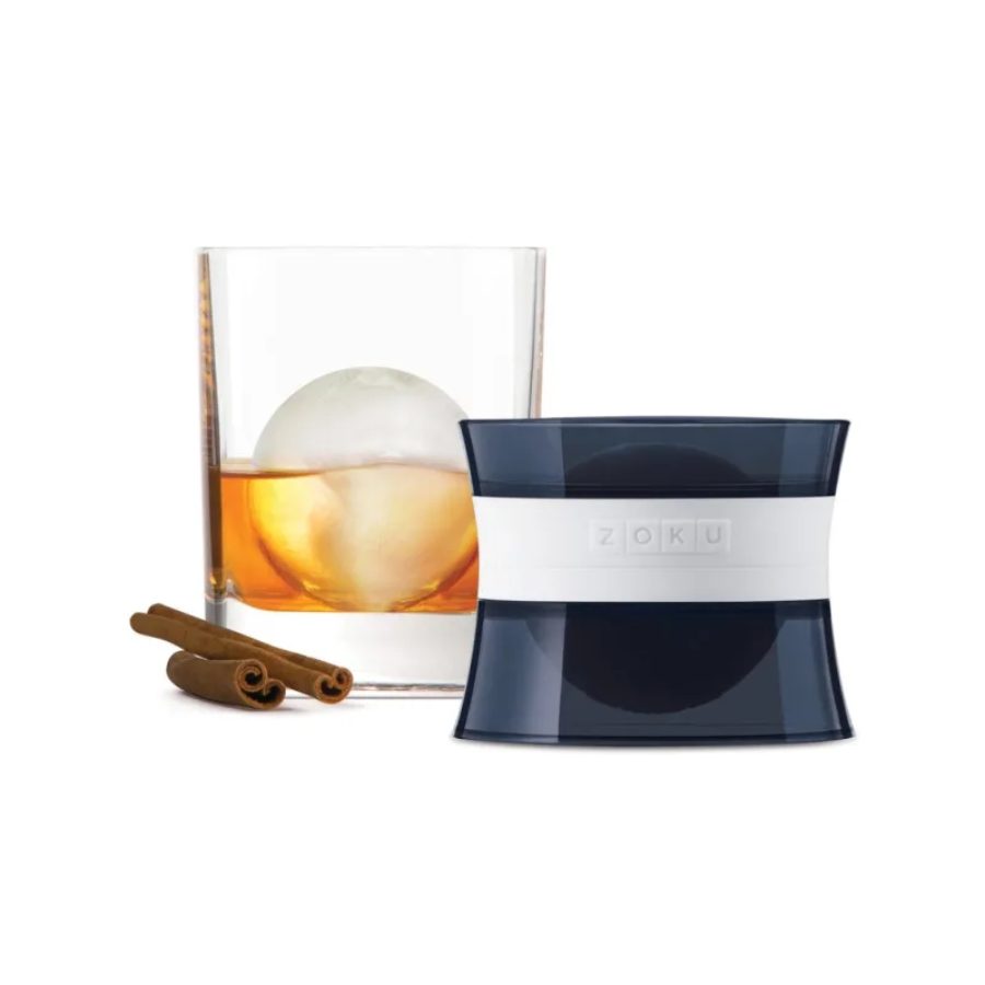 Zoku Ice Mold with cinnamon sticks next to a glass of whiskey on a white background