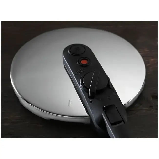 Close-up of a pressure cooker lid with a release valve on a wooden surface