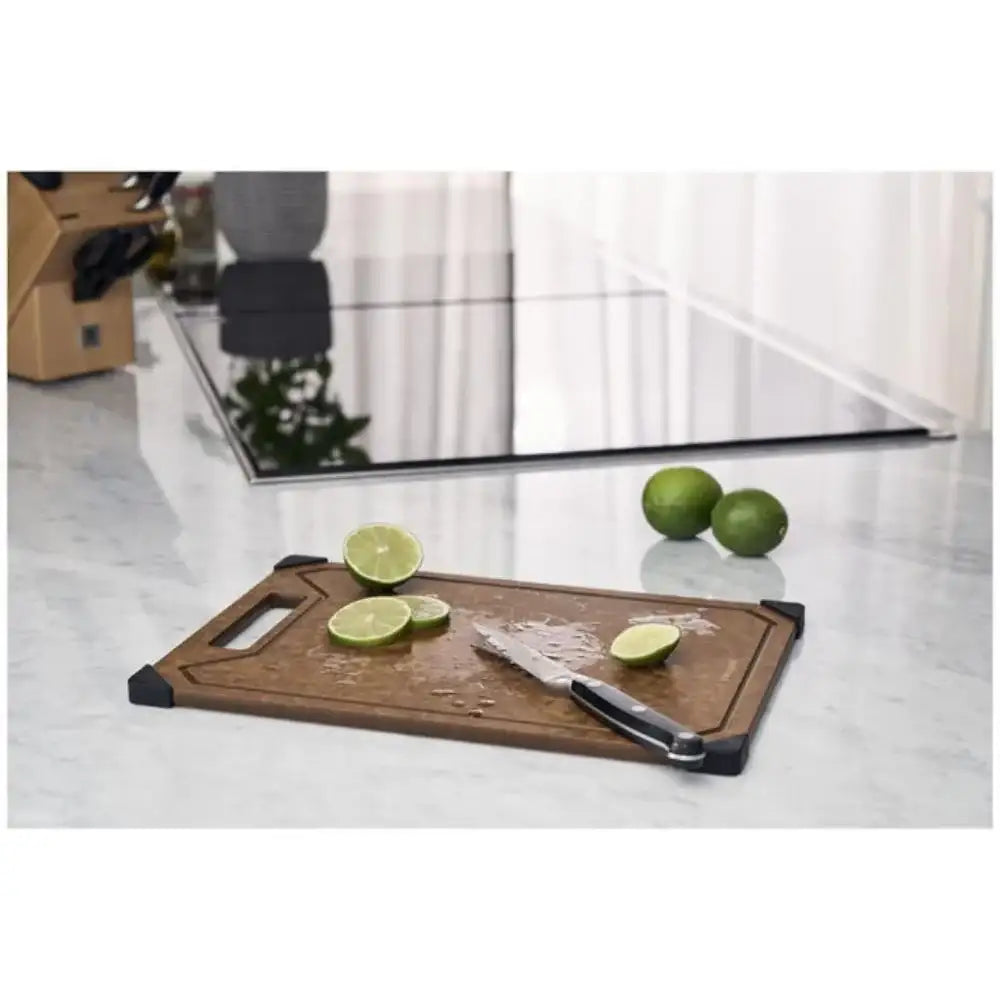 Wooden cutting board with sliced limes and a knife on a marble countertop.