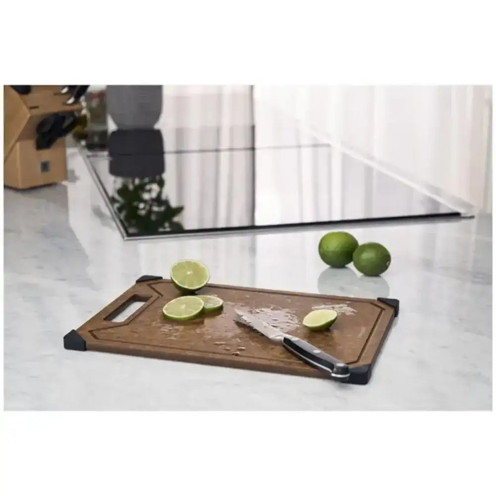 Large brown wood cutting board with black corners, knife, and sliced limes on kitchen counter