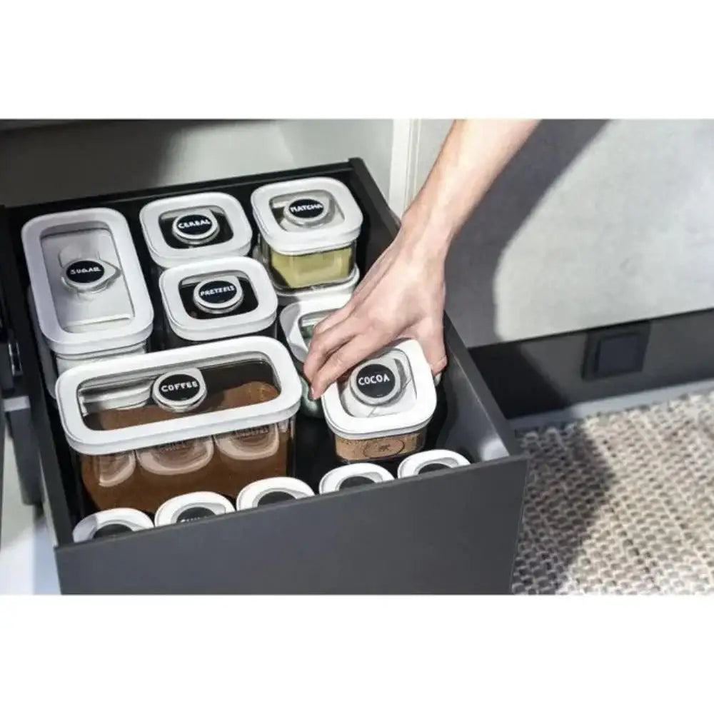 Hand reaching into a drawer with labeled food containers.