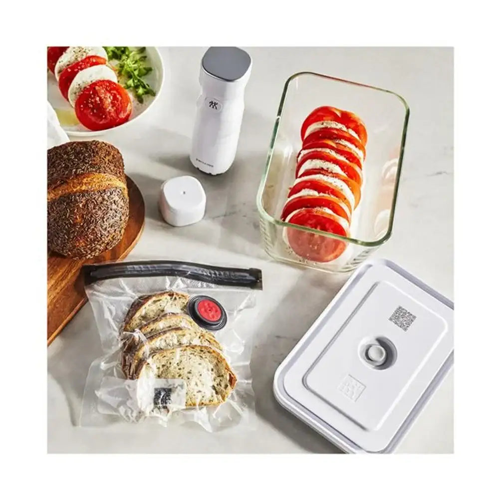 Food storage containers with sliced bread and tomatoes on a white surface