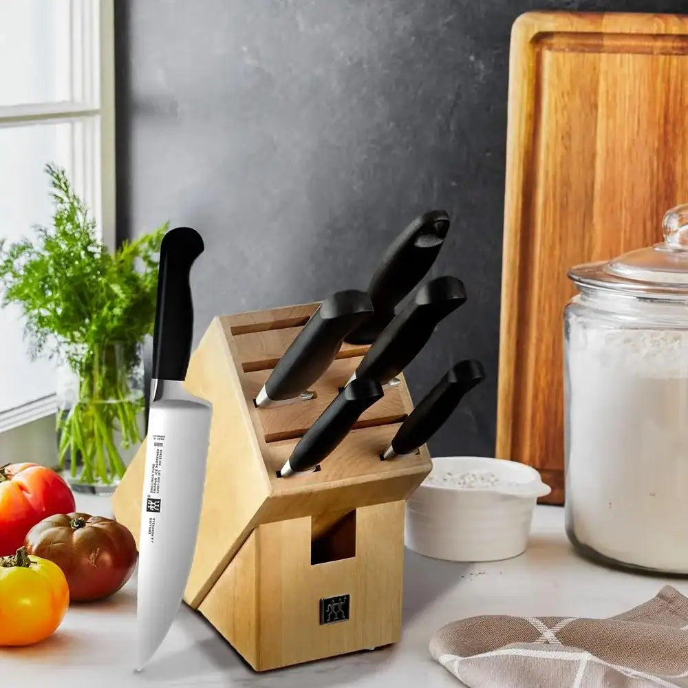 Set of knives in a wooden block on a kitchen counter with fruits and a jar in the background.