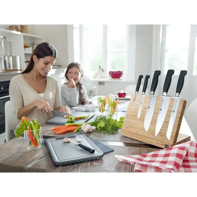 Woman and child preparing food in a kitchen with knives and cutting boards.