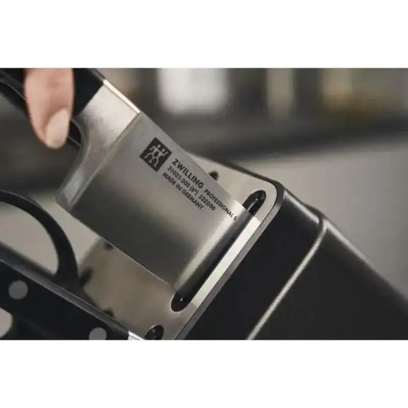 Knife with a visible brand label held by a hand against a blurred background