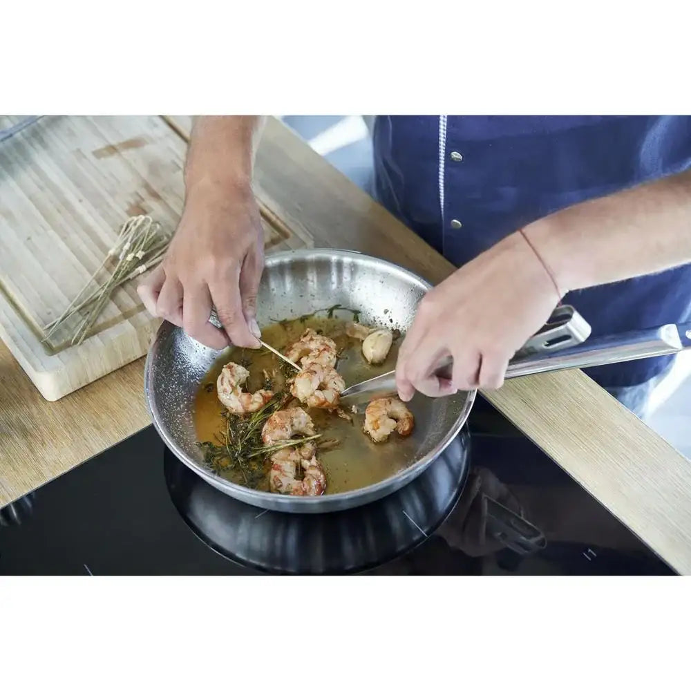 Person cooking shrimp in a pan on a stove