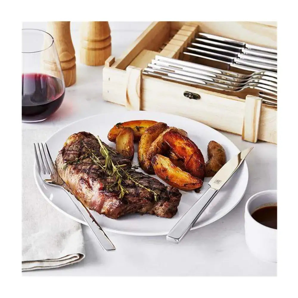 Steak with potatoes on a plate with cutlery, including a wine glass and cup of coffee.