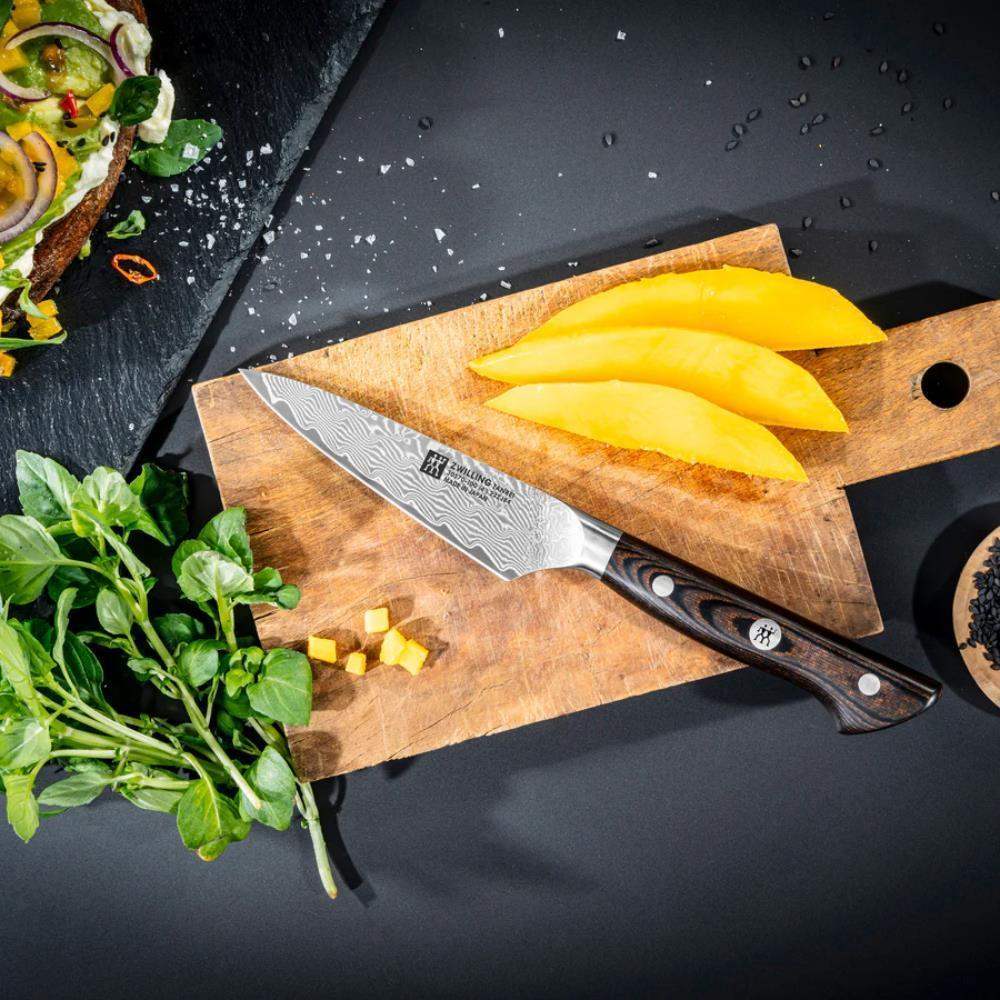 Wooden cutting board with sliced mangoes and a knife on a dark surface