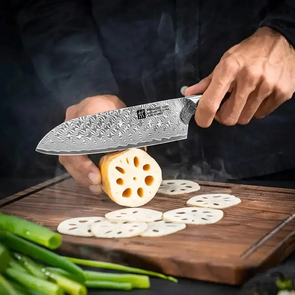 Person slicing lotus root with a chef's knife on a wooden cutting board.