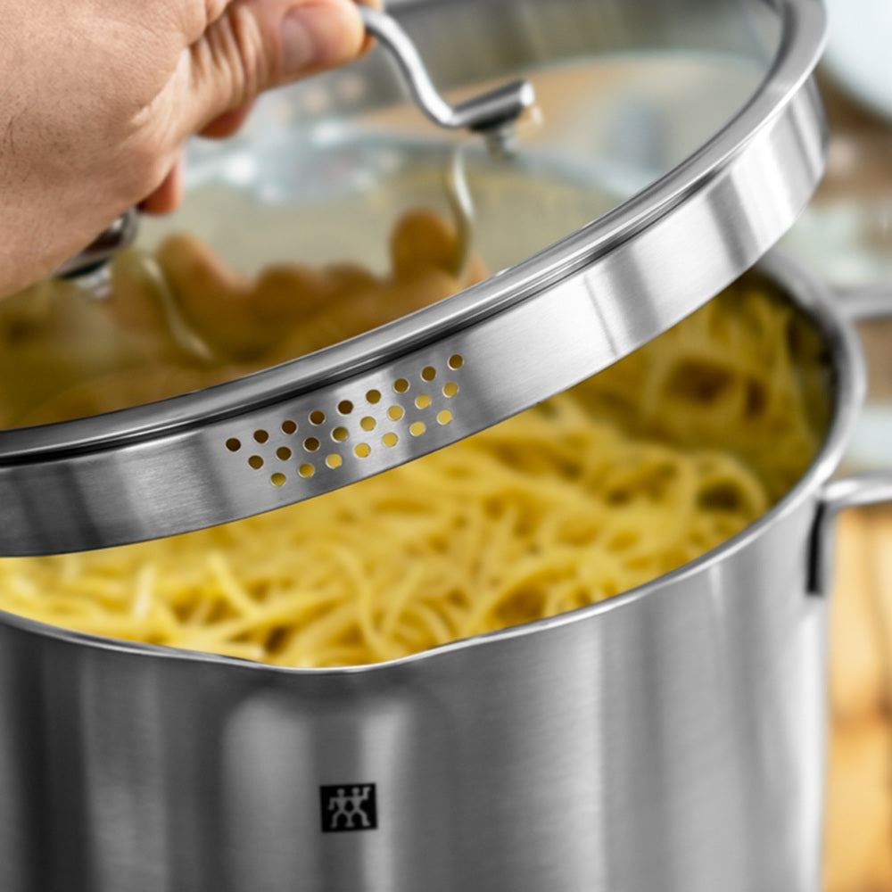 Stainless steel pot with lid being lifted to reveal cooked pasta inside
