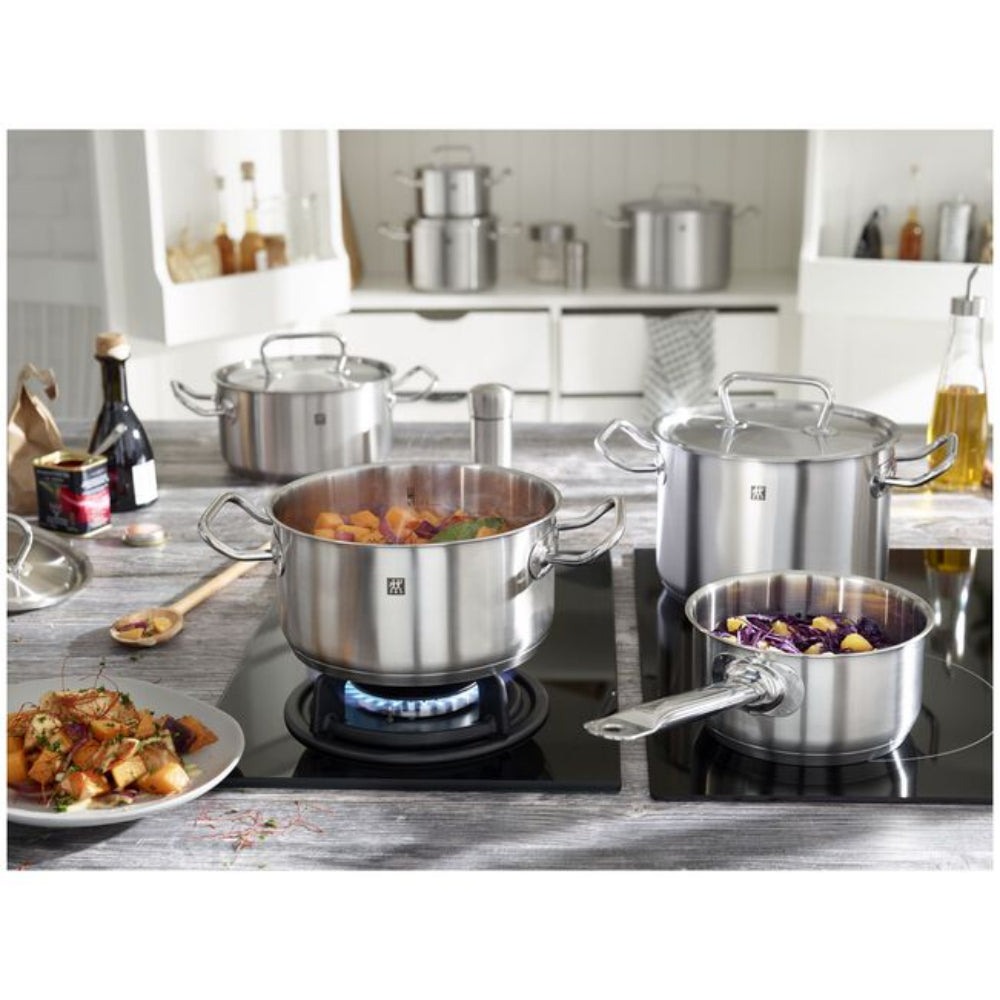 A set of stainless steel cookware pots and a saucepan on a black induction cooktop in a modern kitchen setting. The cookware features the ZW logo on the side of the pots.