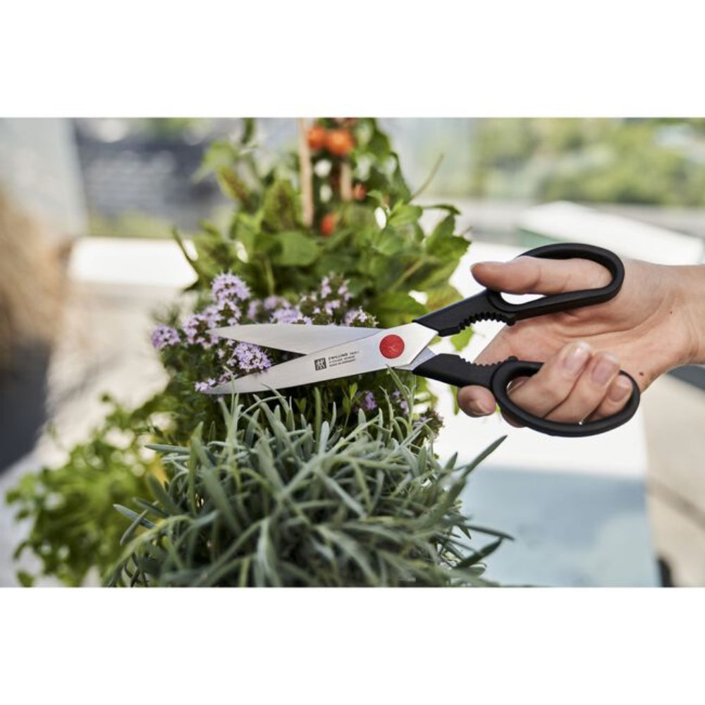 Person using garden shears to trim a plant with a blurred outdoor background
