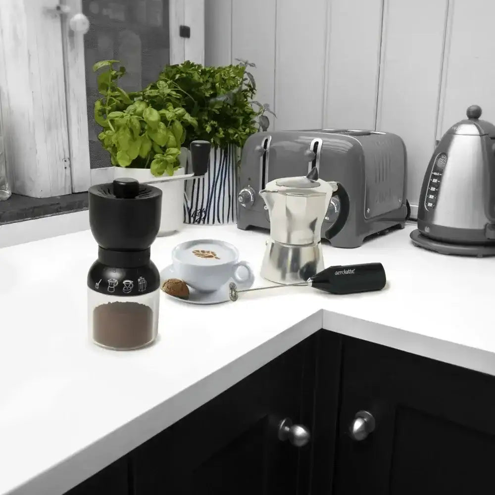 Kitchen counter with coffee-making equipment including a grinder, coffee press, and toaster.