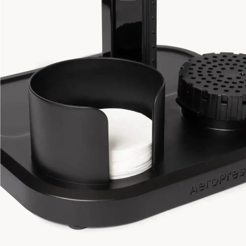Black AeroPress coffee maker with a white filter on a white background