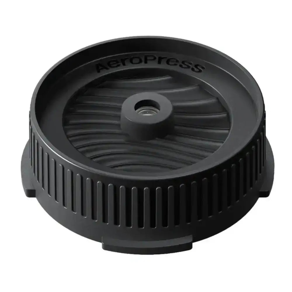 Black AeroPress coffee brewing component on a white background