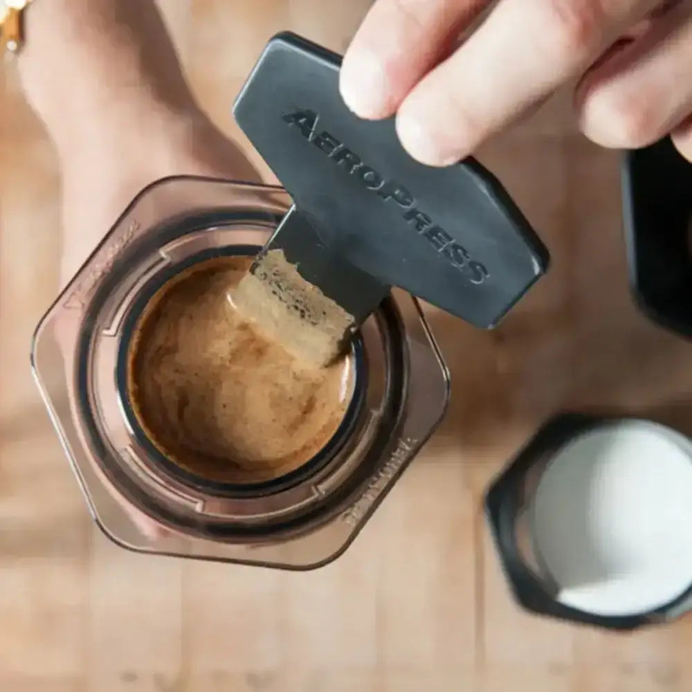 Person using an Aeropress to make coffee on a wooden surface