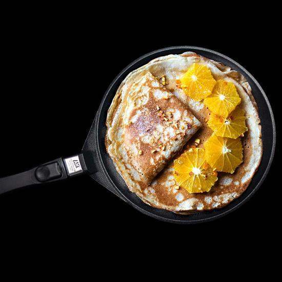 Golden-brown crepe in a black amt gastroguss non-stick crepe pan 28cm garnished with vibrant orange slices