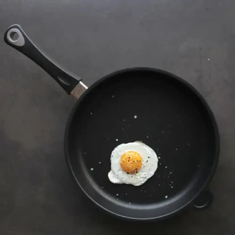 Fried egg in a black frying pan on a dark surface