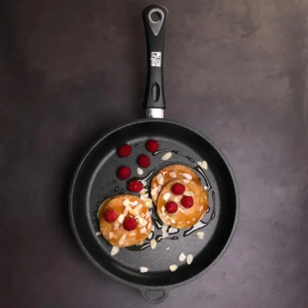 Frying pan with pancakes and berries on a dark surface