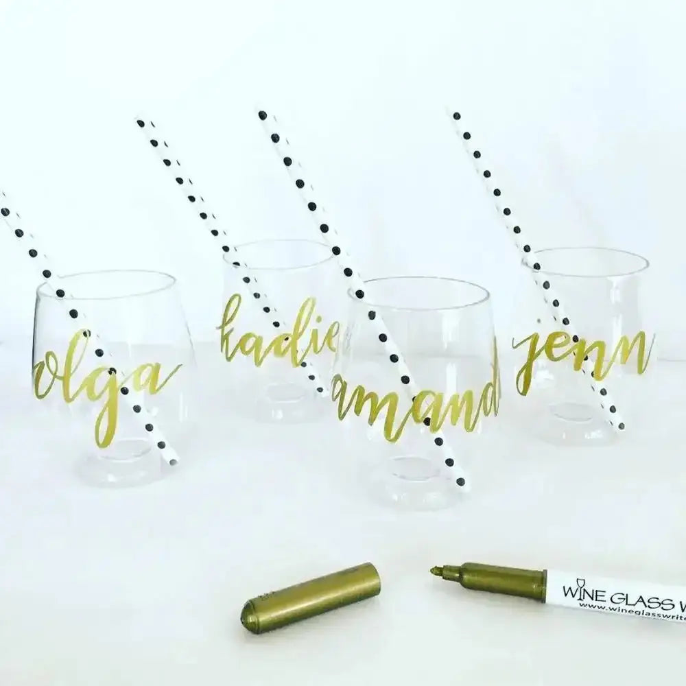 Clear wine glasses with gold names and black polka dots, with a marker and cap on a white background.