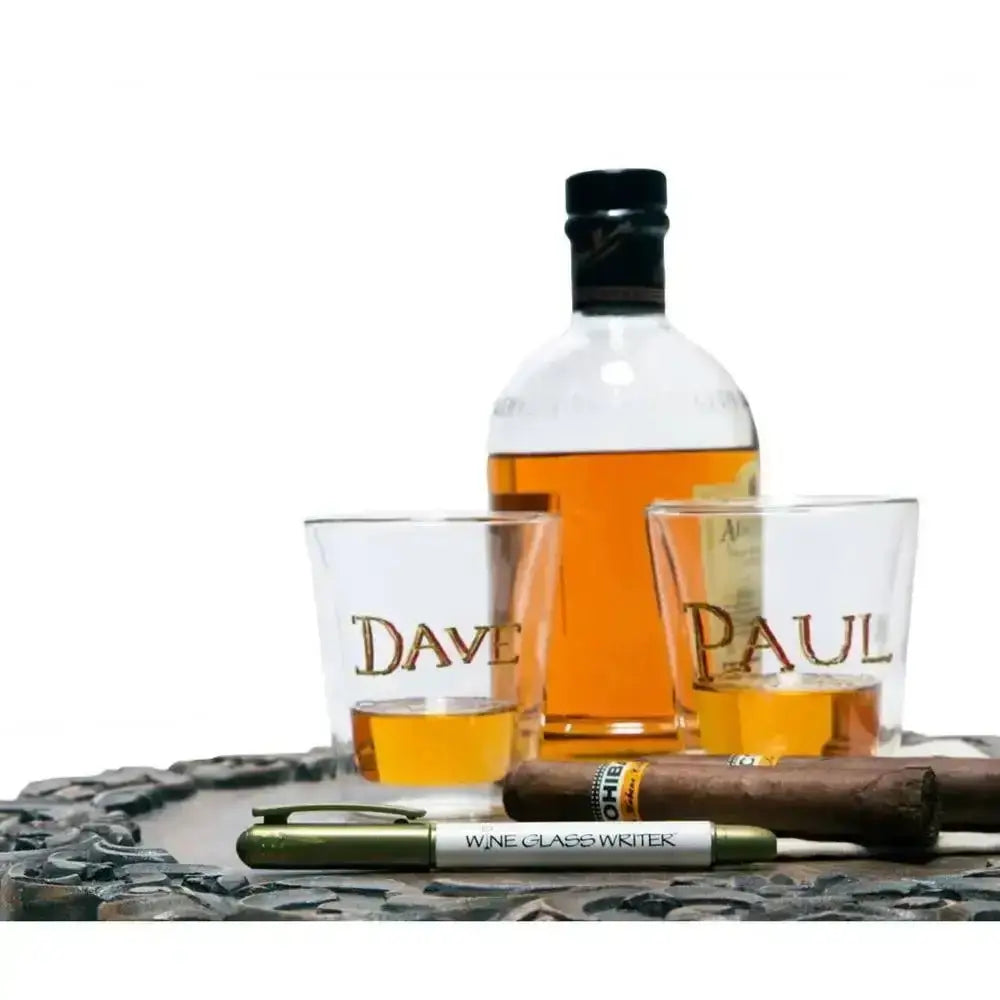 Bottle of whiskey with two branded shot glasses and a cigar on a decorative tray.
