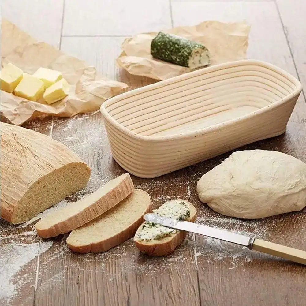 Rectangular bread proofing basket with dough, sliced bread, butter, and knife on wooden table