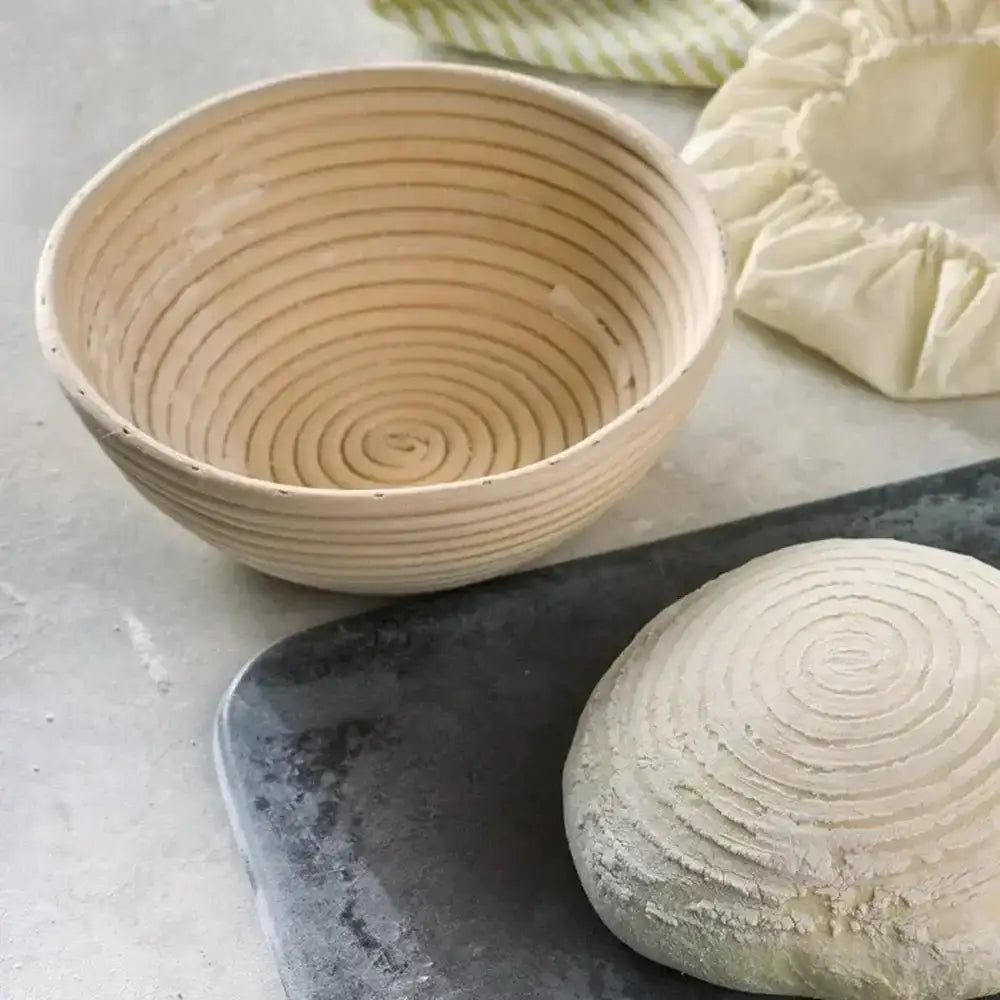 Bread proofing basket with a loaf of bread on a stone surface