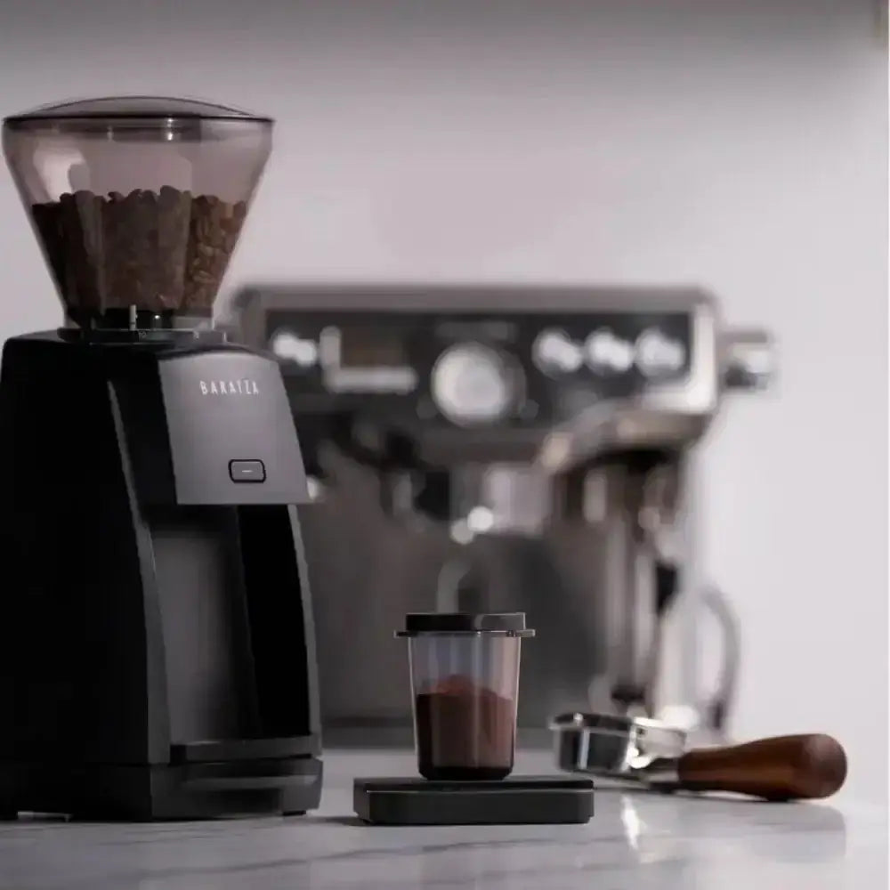 Coffee grinder and espresso machine on a countertop with a blurred background