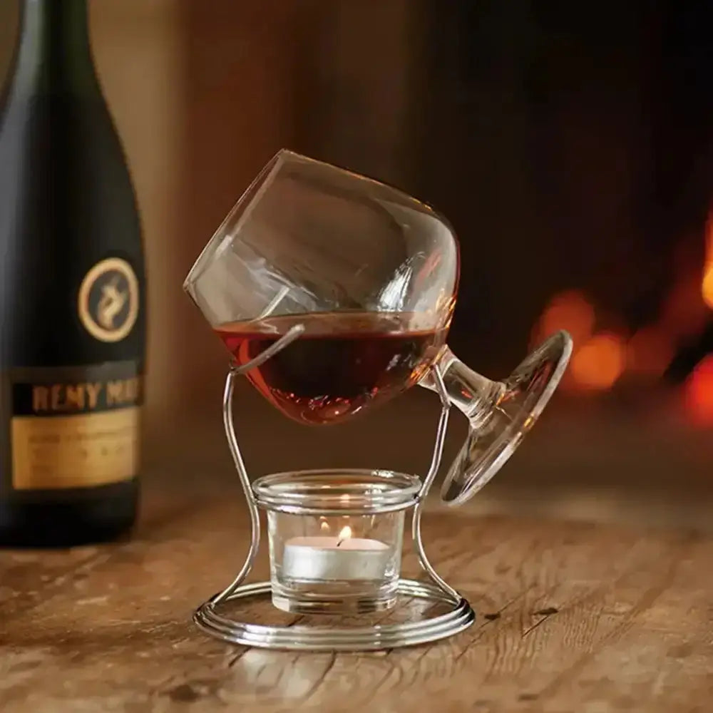 Glass with red liquid and candle on a wooden surface with a blurred background