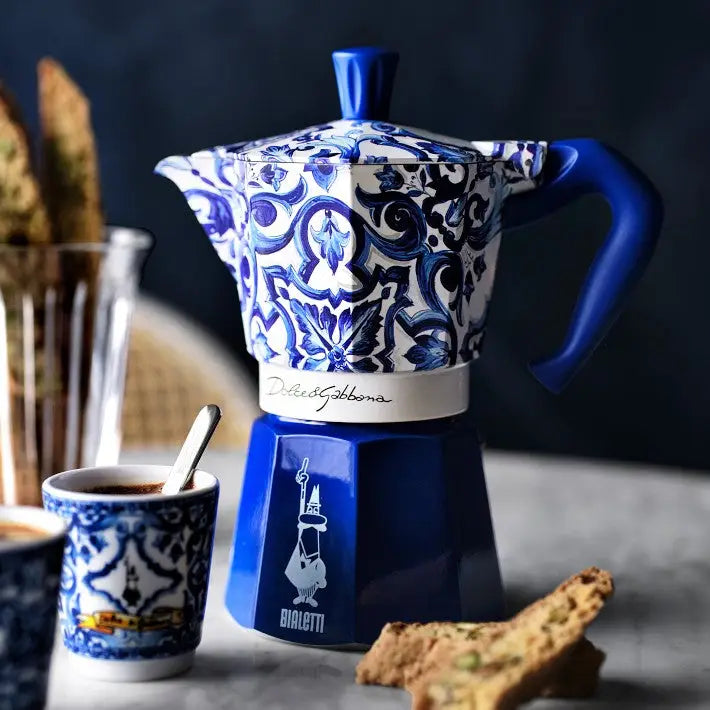 Blue and white patterned coffee maker with a cup on a dark background