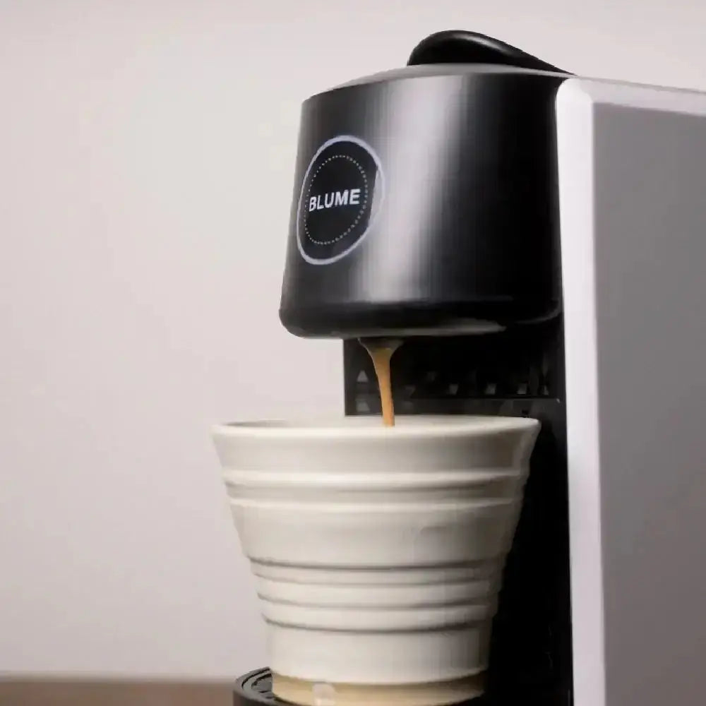Blume 2-Step Pro capsule coffee machine in white brewing coffee into ceramic cup, Cookin Stores kitchenware.
