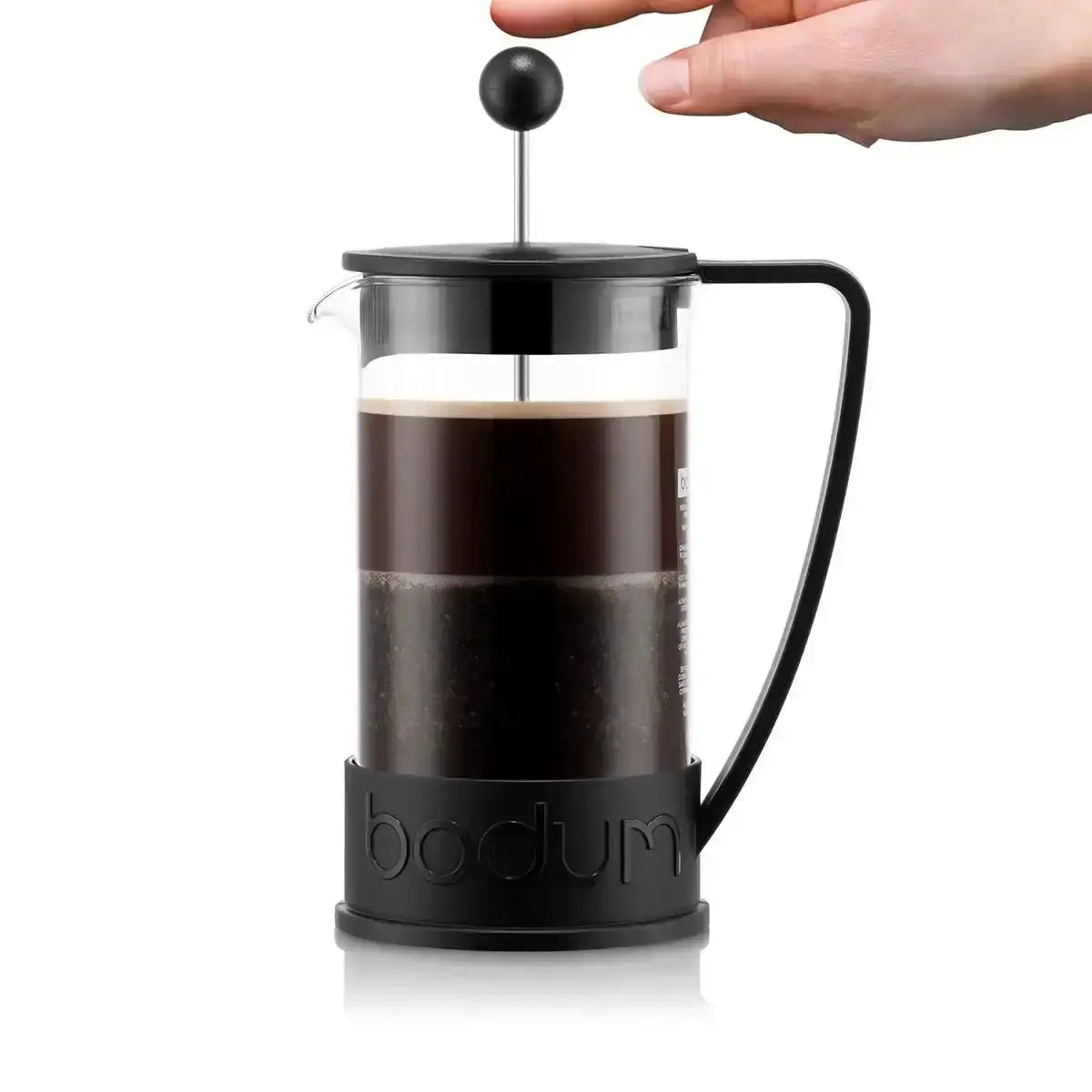 Bodum French press with coffee being pressed, on a white background