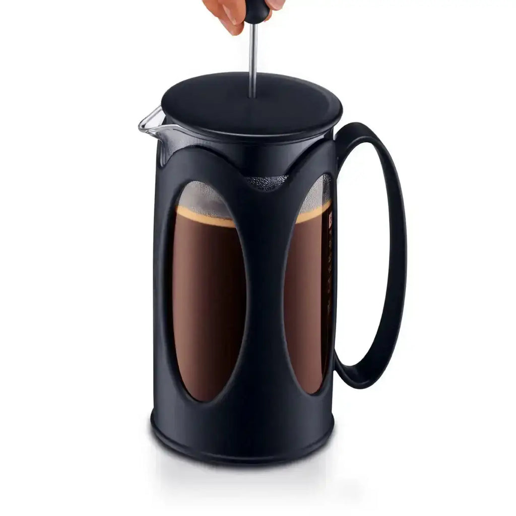 Black French press with coffee being stirred on a white background