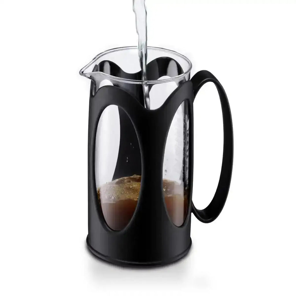 Black French press with coffee being poured into it on a white background